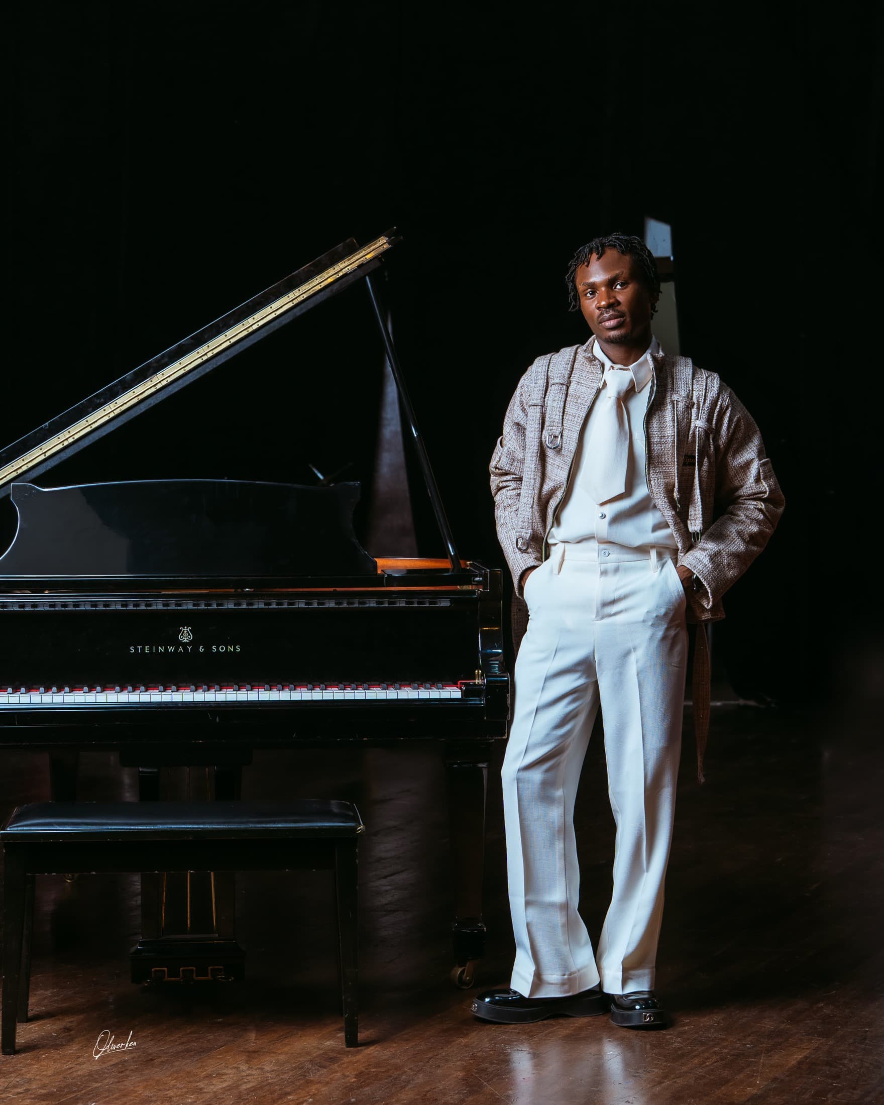 Victor Eze standing beside a Steinway grand piano